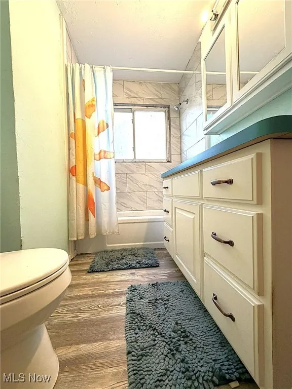 Full bathroom with vanity, light wood-type flooring, and shower / bath combo