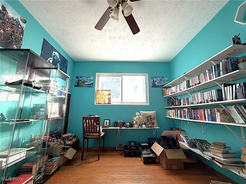 Living area featuring light wood-type flooring, a ceiling fan, and a textured ceiling