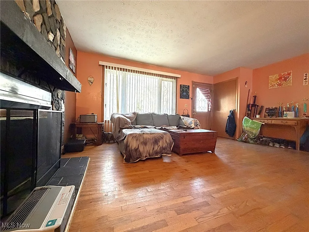 Living area featuring wood-type flooring, a textured ceiling, and a tile fireplace