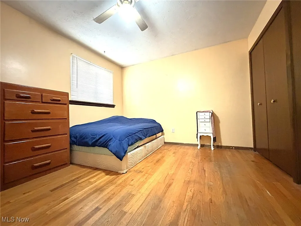 Bedroom featuring light wood-style flooring, ceiling fan, a closet, and a textured ceiling