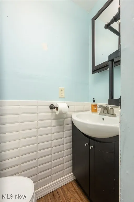Bathroom with vanity, wood finished floors, tile walls, and wainscoting