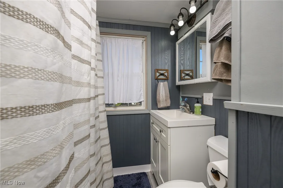 Bathroom with curtained shower, vanity, and wood walls