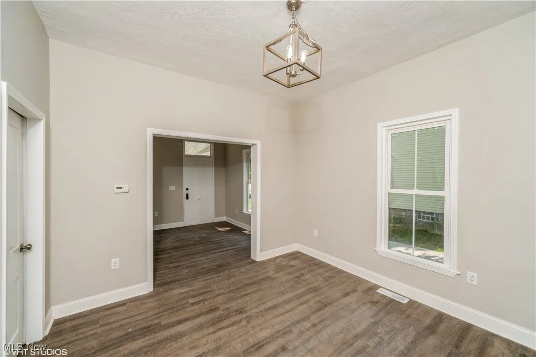 Unfurnished dining area with dark wood-type flooring, a textured ceiling, and a chandelier