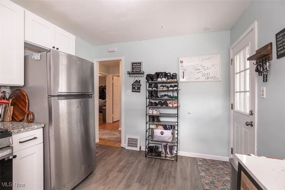 Kitchen with white cabinetry, light stone countertops, and dark wood-style floors