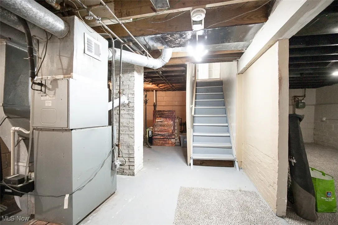 Unfinished basement with heating unit and stairs