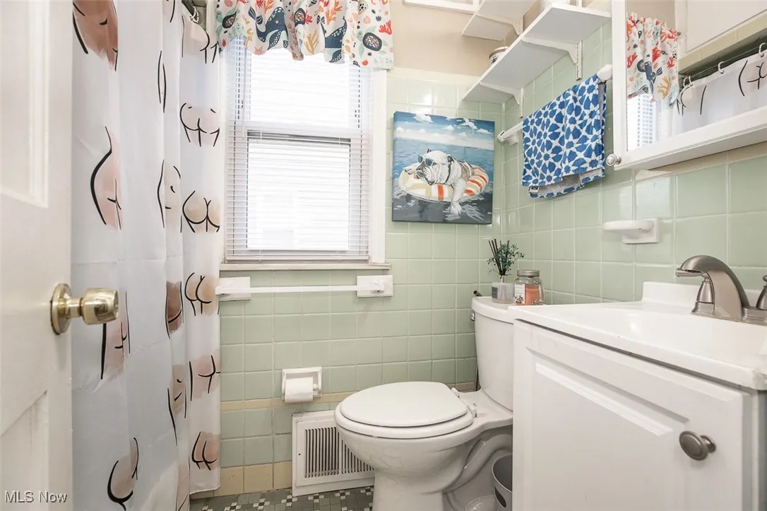 Full bathroom featuring tile walls, vanity, a shower with curtain, and tile patterned flooring