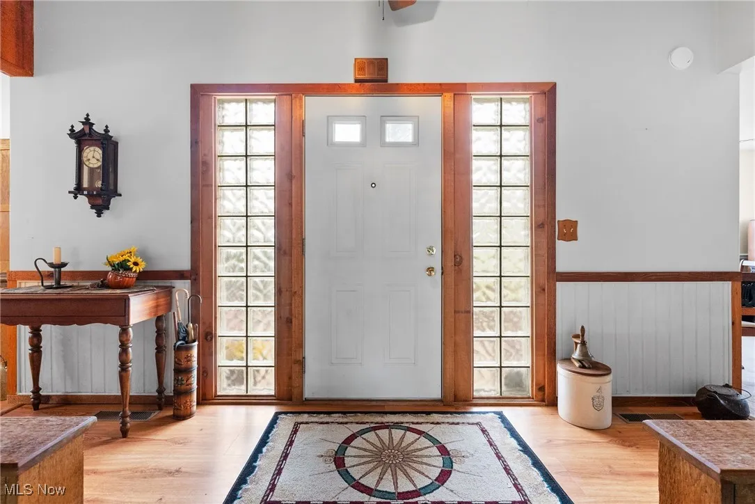 Entryway with light wood-style floors and a wainscoted wall