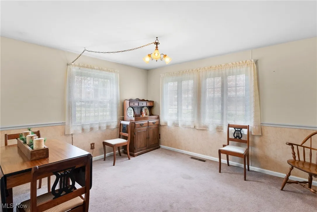 Living area featuring carpet, wainscoting, and a chandelier