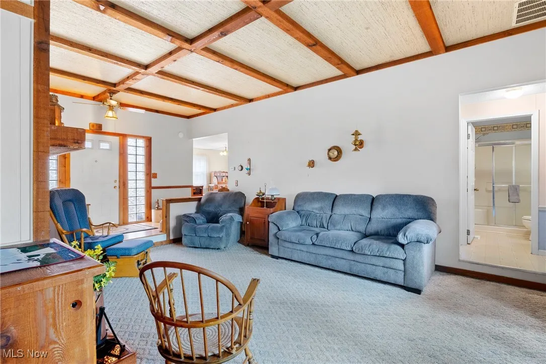 Carpeted living area featuring beamed ceiling