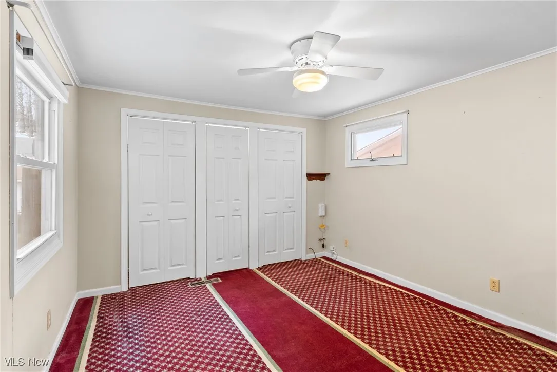 Unfurnished bedroom with crown molding, a closet, carpet, and a ceiling fan