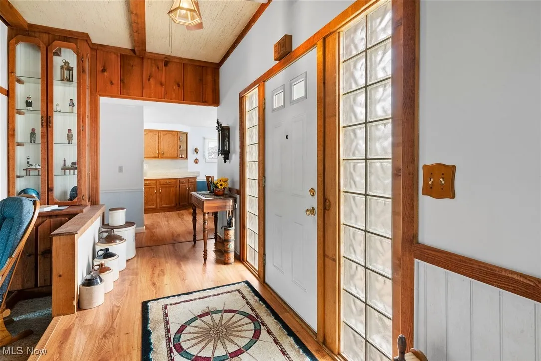 Foyer entrance with beamed ceiling and light wood-style floors
