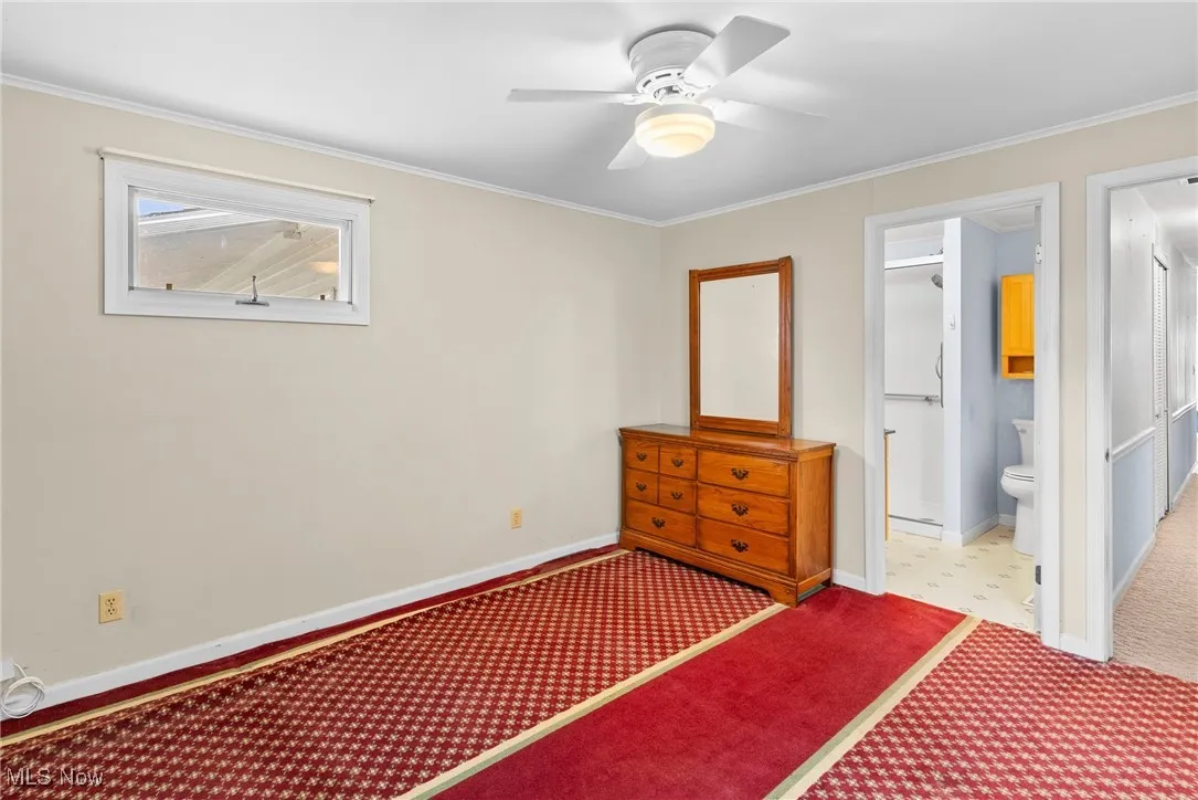 Carpeted bedroom with crown molding, a ceiling fan, and ensuite bathroom