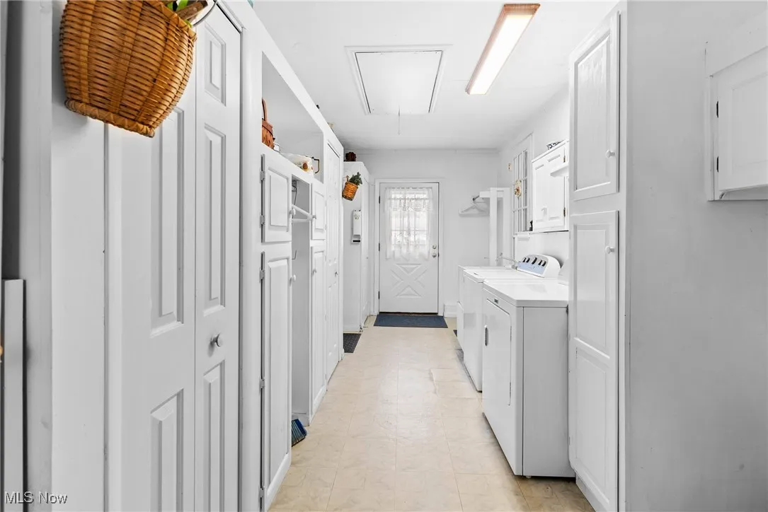 Laundry room featuring attic access, washer and clothes dryer, cabinet space, and light flooring