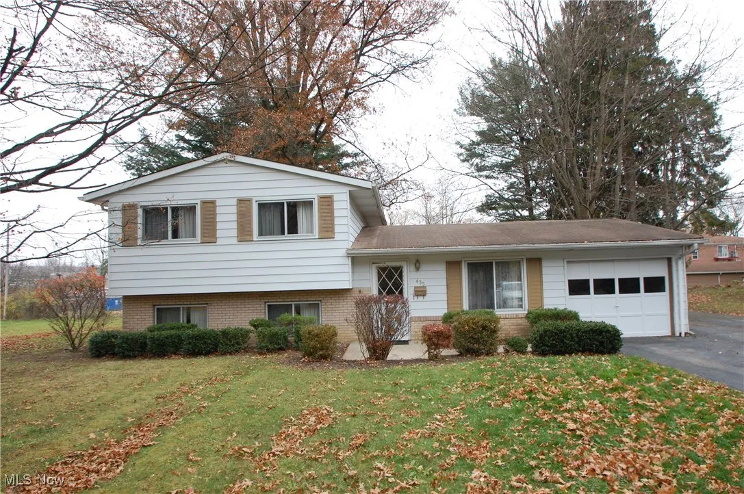 Split level home with brick siding, a front yard, and an attached garage