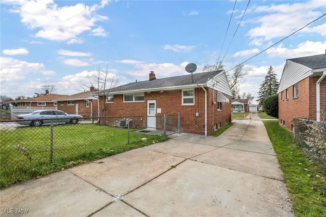 Back of property with brick siding, a chimney, and driveway
