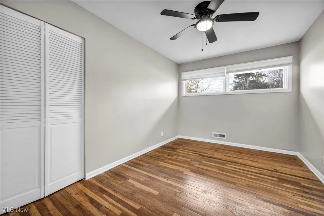Unfurnished bedroom featuring hardwood / wood-style floors, a closet, and ceiling fan