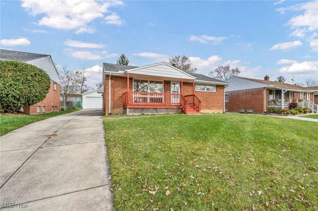 Ranch-style home with a front yard, an outbuilding, brick siding, and covered porch