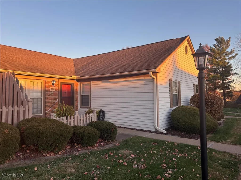 View of front facade with a front lawn, roof with shingles, and brick siding