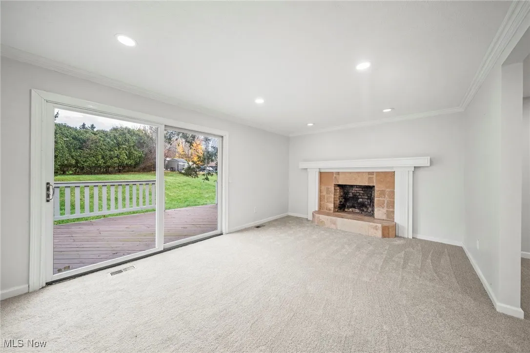 Unfurnished living room featuring ornamental molding, carpet, recessed lighting, and a fireplace