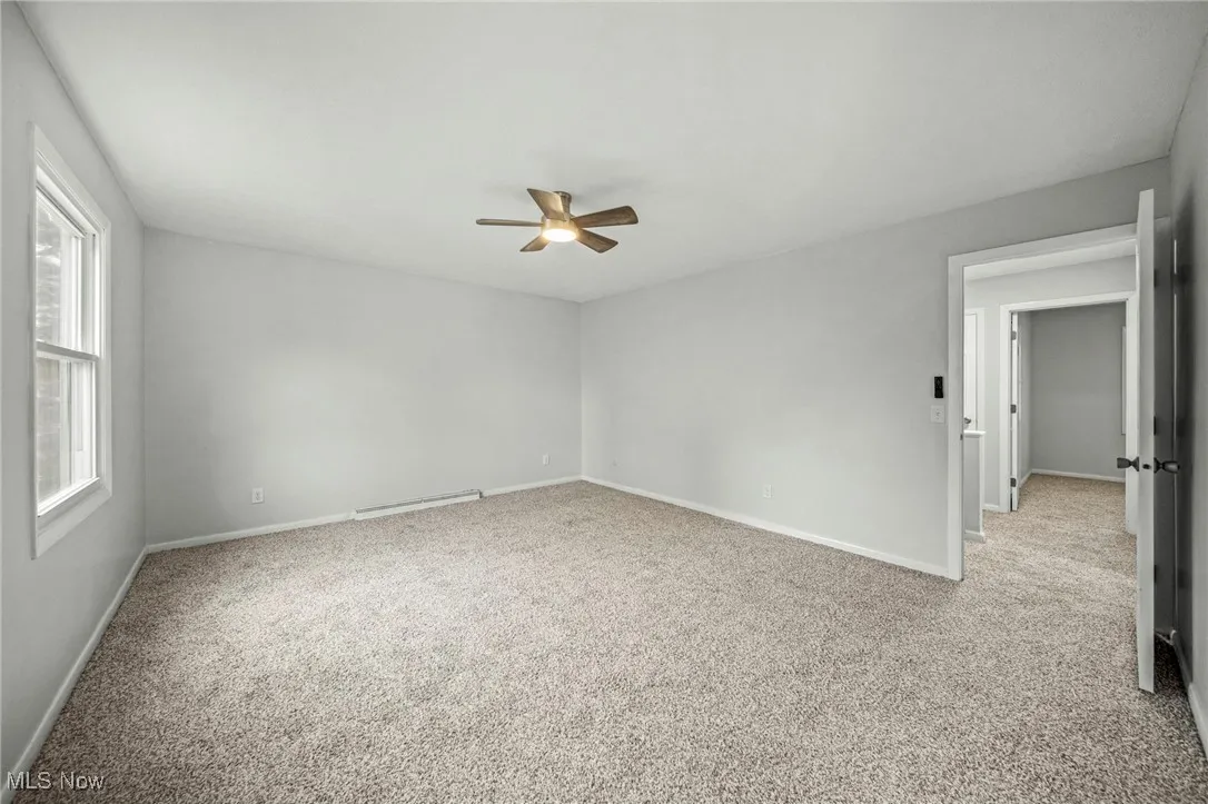 Carpeted empty room featuring a baseboard radiator and a ceiling fan