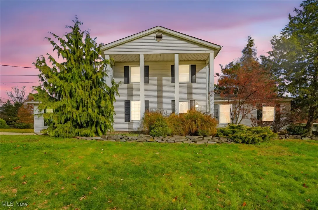 Greek revival house featuring a front lawn and covered porch