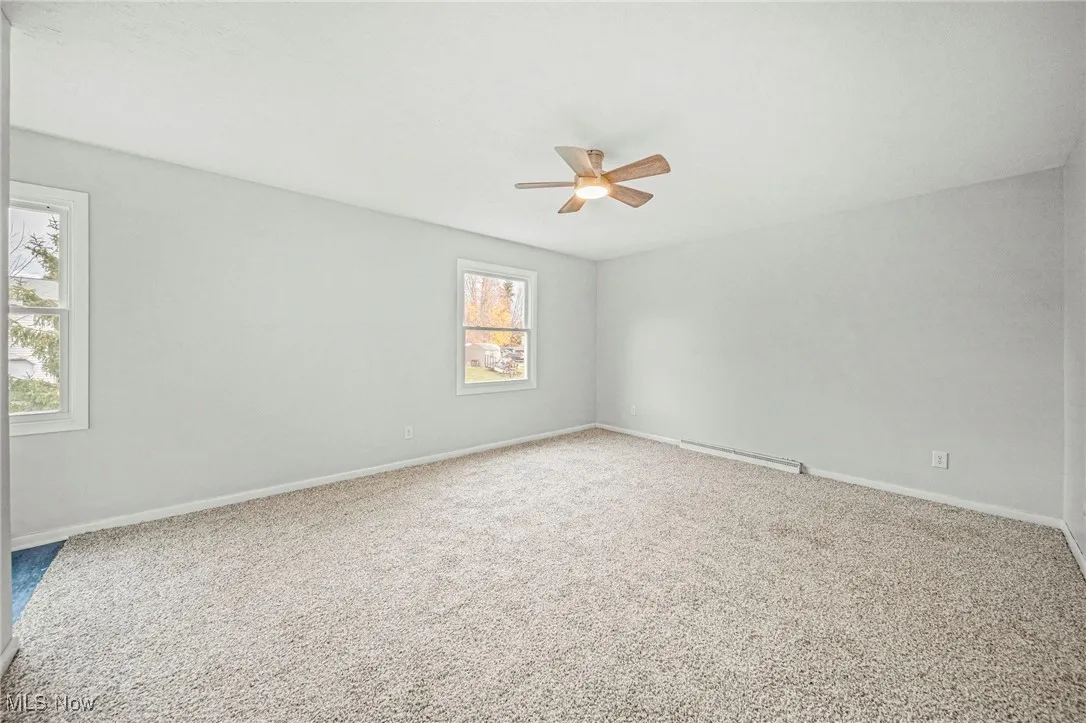 Carpeted spare room featuring baseboards and a baseboard radiator