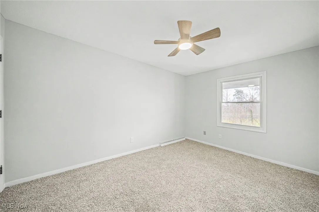 Empty room with carpet floors and ceiling fan