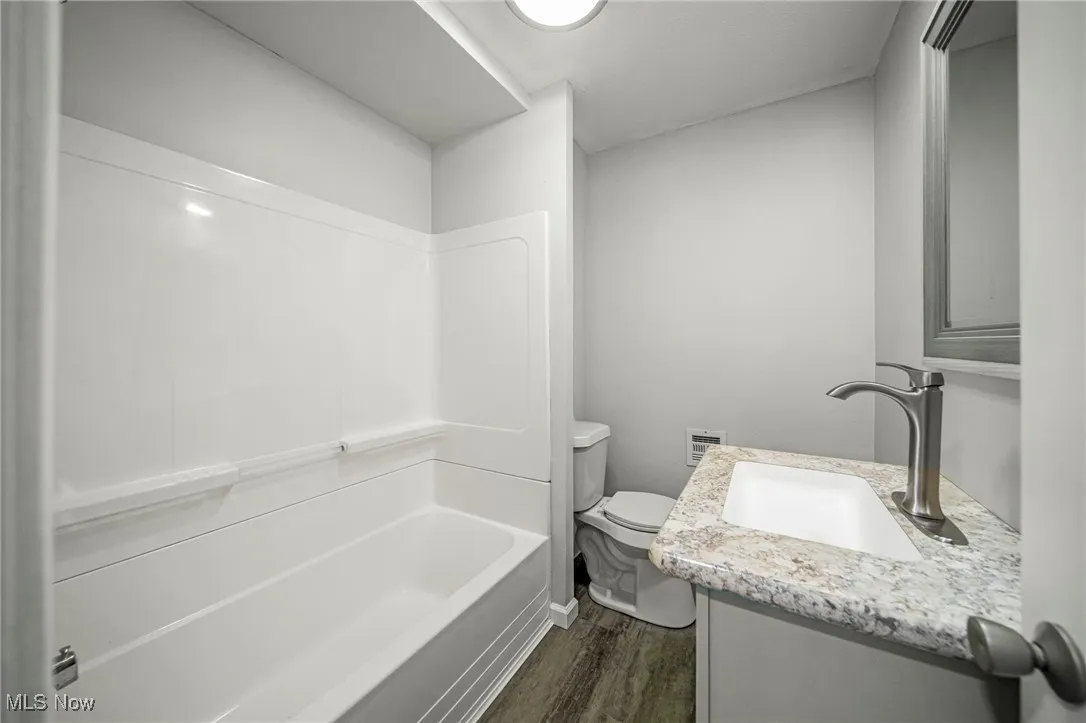 Full bathroom with dark wood-style floors, vanity, and shower / bathtub combination