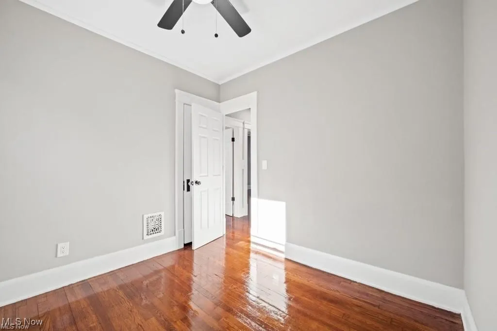 Spare room featuring hardwood / wood-style flooring, ornamental molding, and ceiling fan