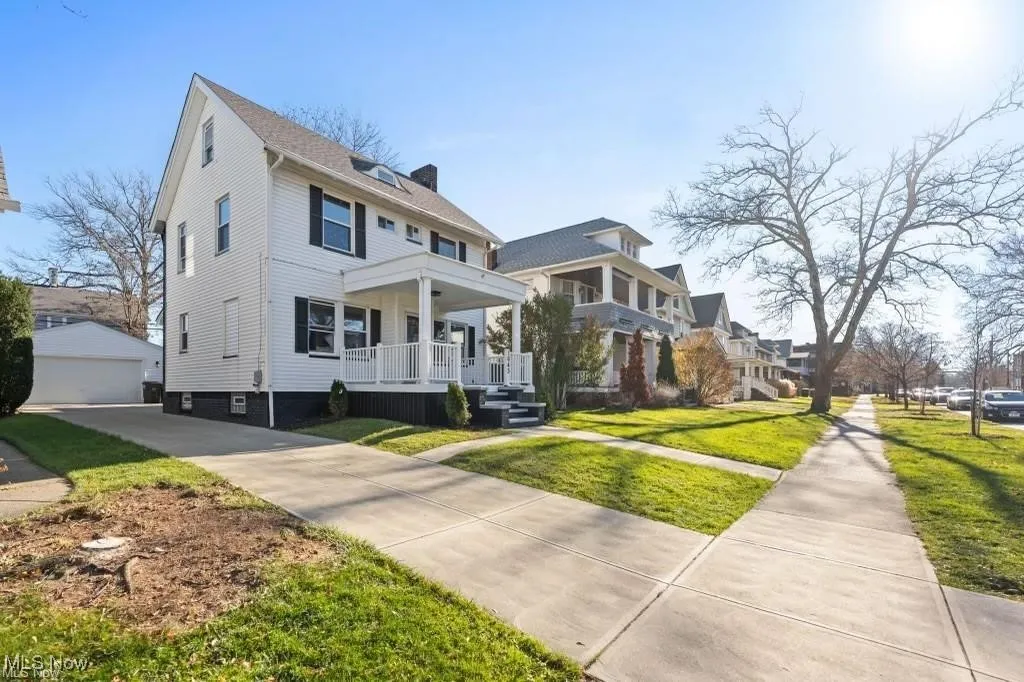 Traditional style home with covered porch, a front lawn, an outdoor structure, a chimney, and a detached garage