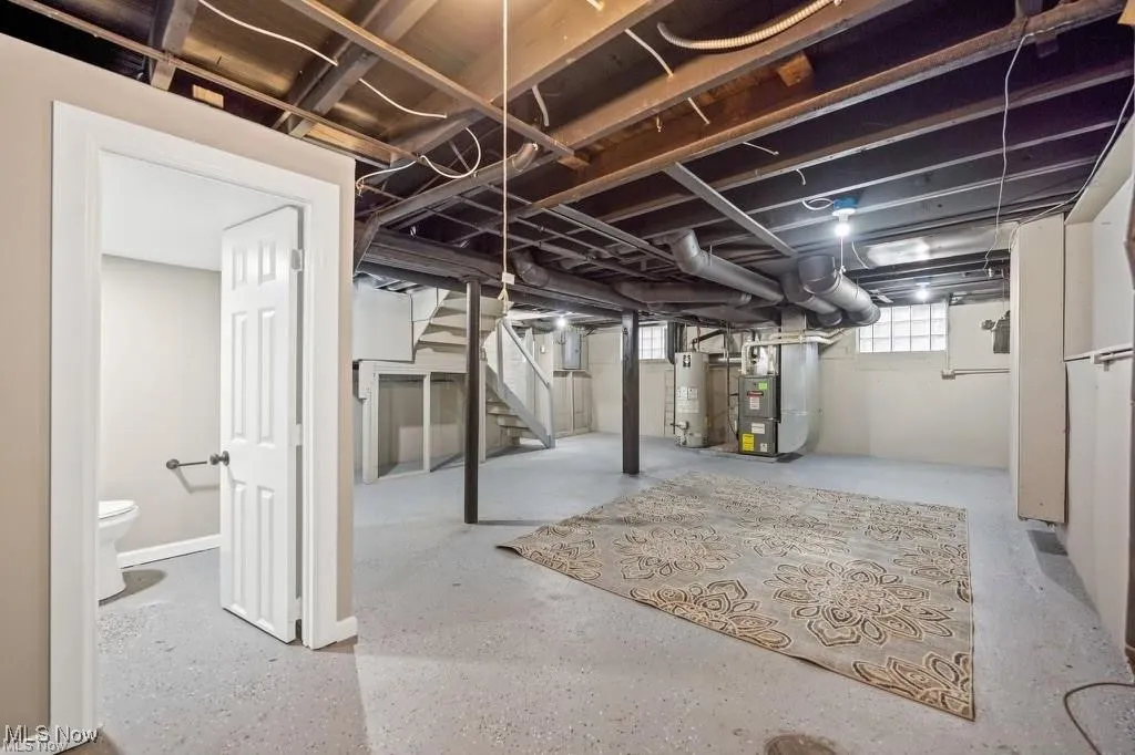 Basement featuring stairs, water heater, and heating unit