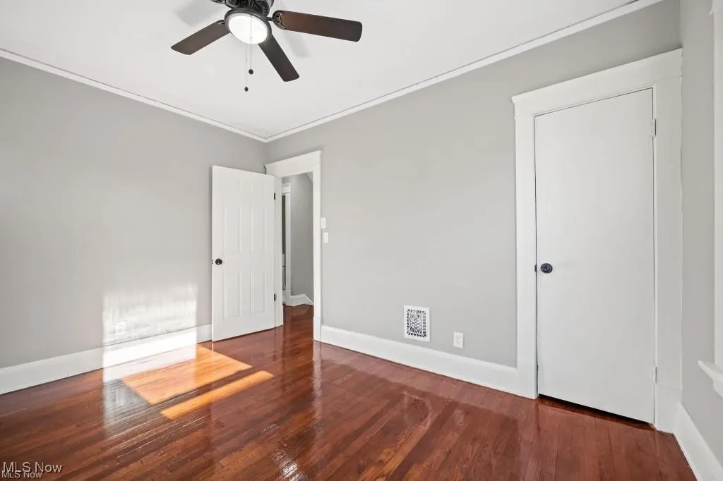Spare room featuring dark wood-type flooring and ornamental molding