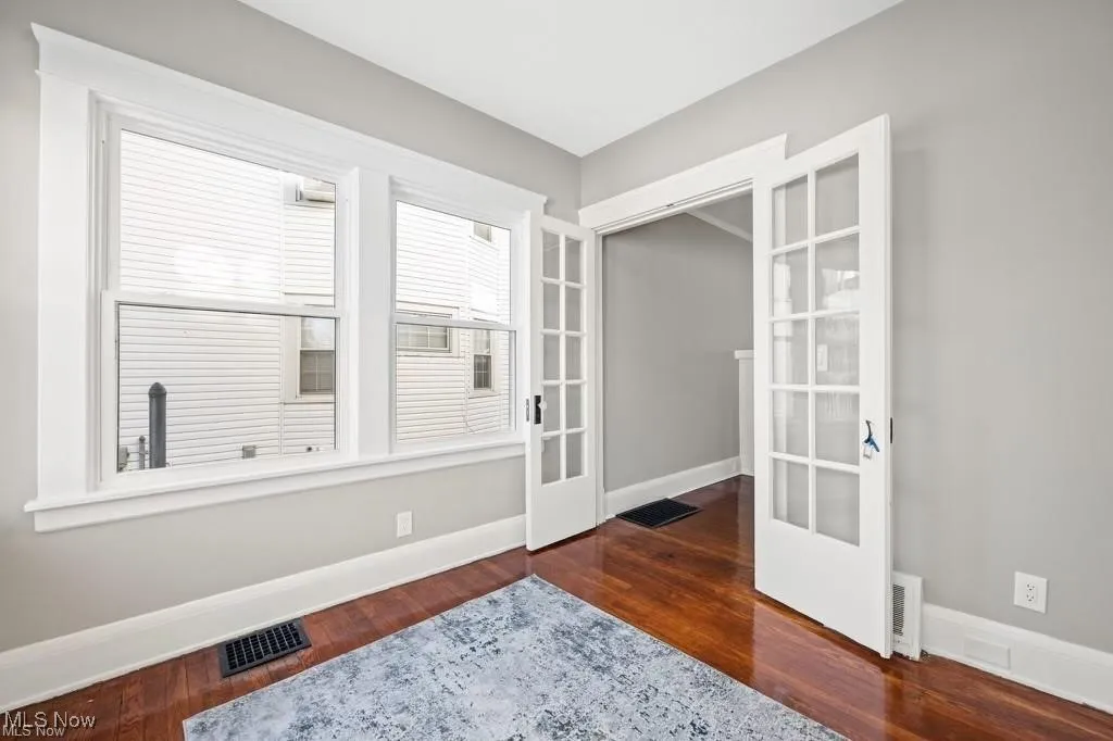 Unfurnished room featuring french doors and dark wood-style floors