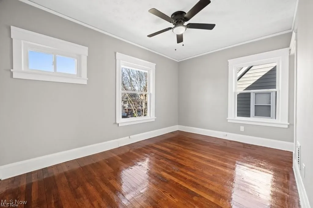 Unfurnished room with ornamental molding, dark wood finished floors, and a ceiling fan