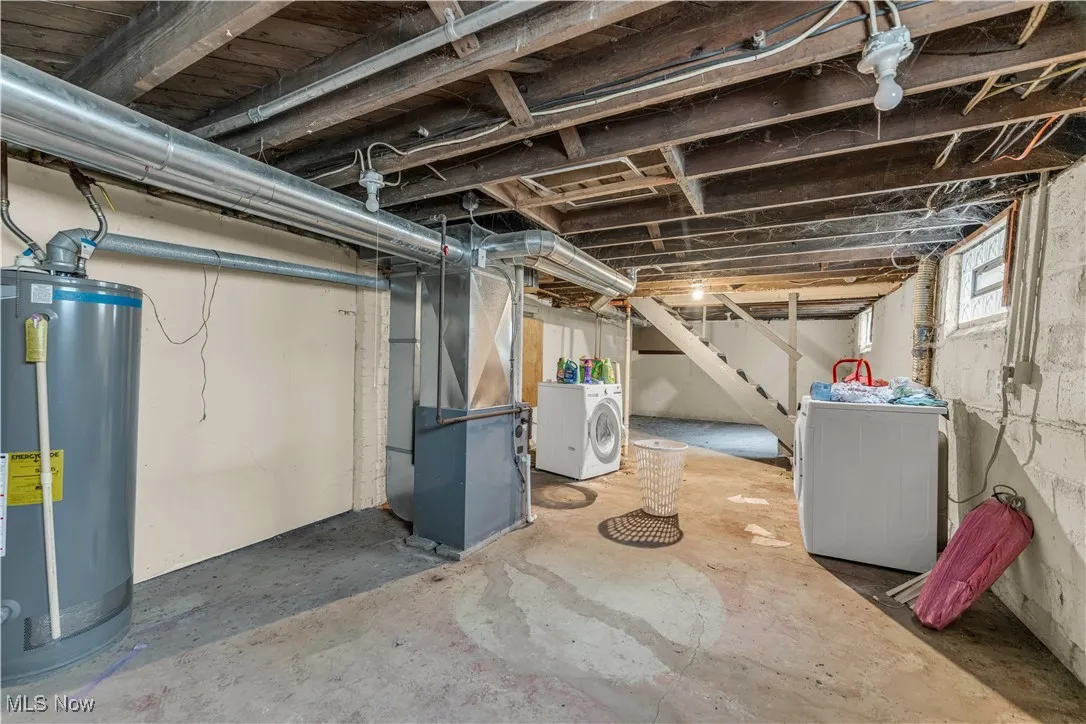 Basement featuring gas water heater, stairs, heating unit, and independent washer and dryer