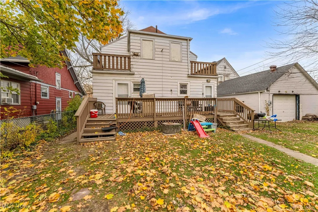 Rear view of property featuring a wooden deck, a balcony, an outbuilding, and a garage