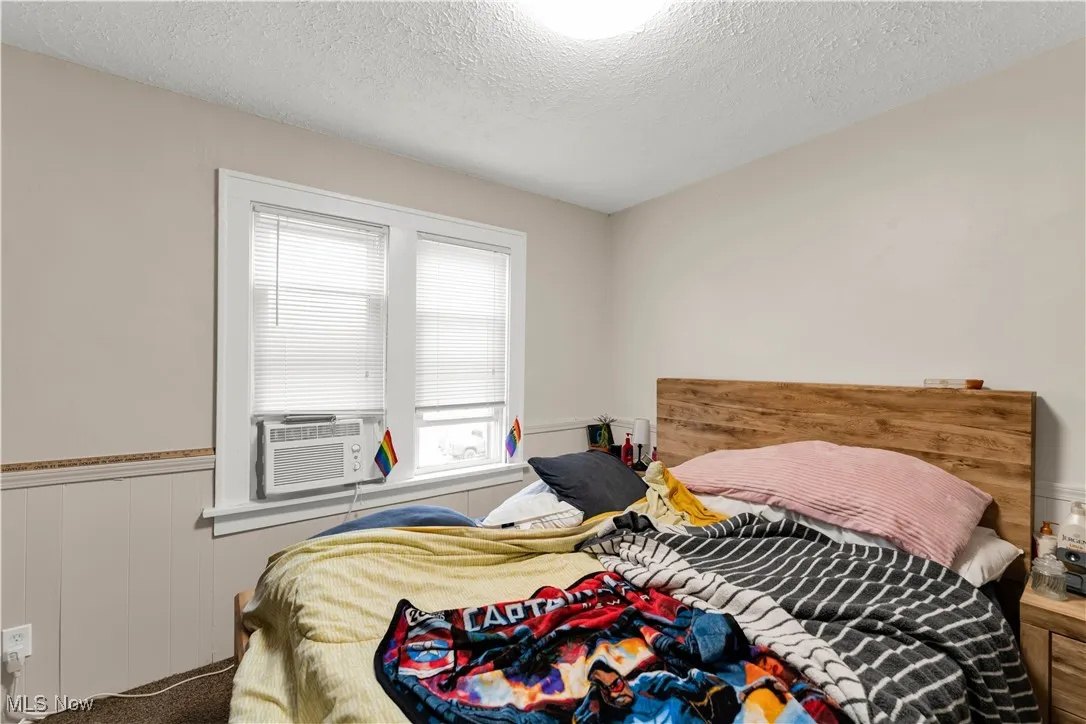 Bedroom featuring wainscoting, a textured ceiling, carpet floors, and cooling unit