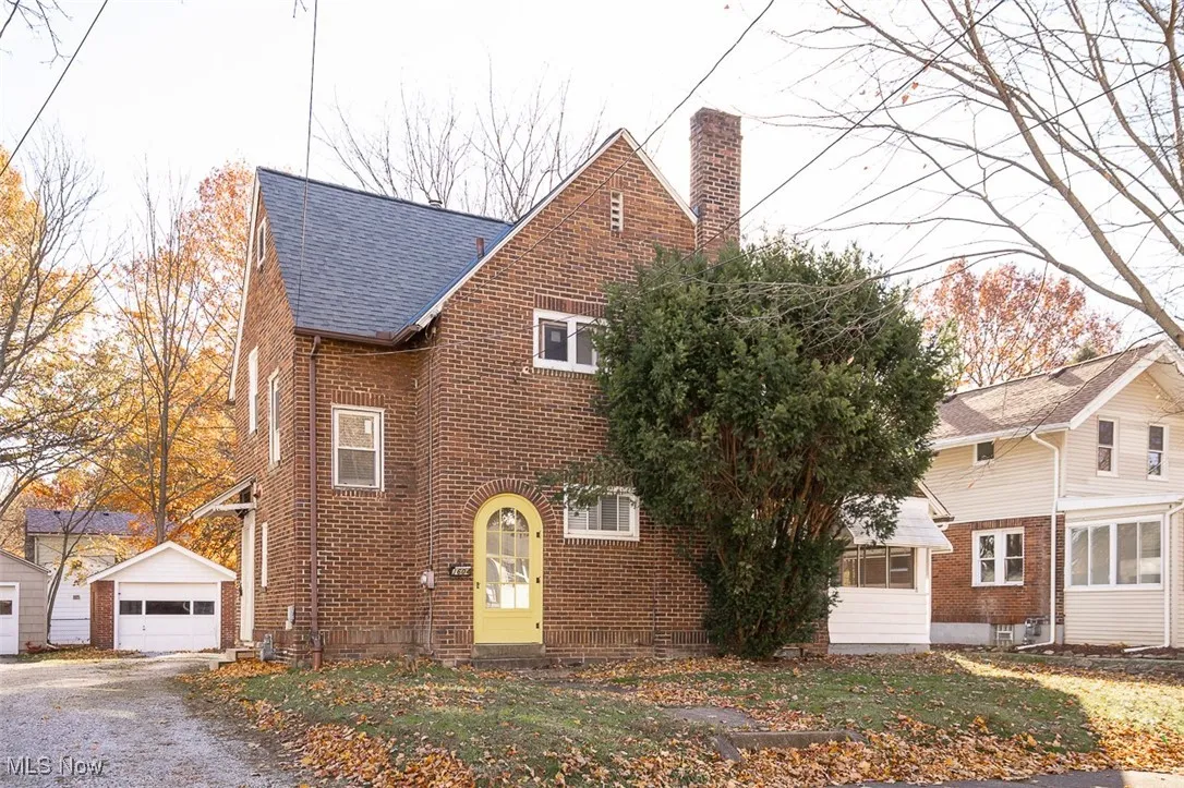 View of front facade featuring an outbuilding, a chimney, a detached garage, and brick siding