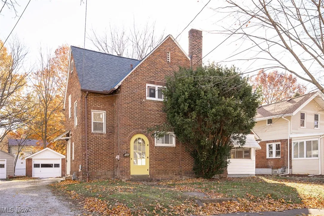 View of front of home featuring an outdoor structure, a chimney, a garage, and brick siding