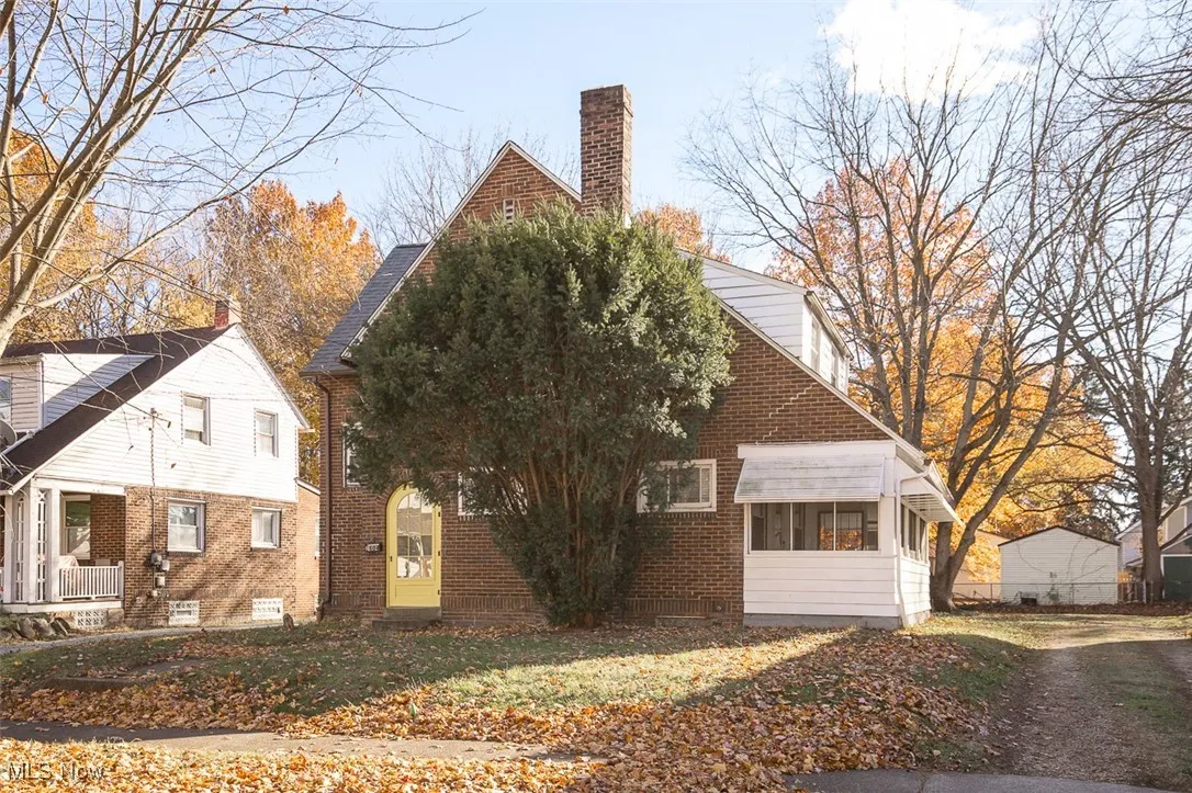 View of property exterior featuring a chimney, brick siding, and a sunroom