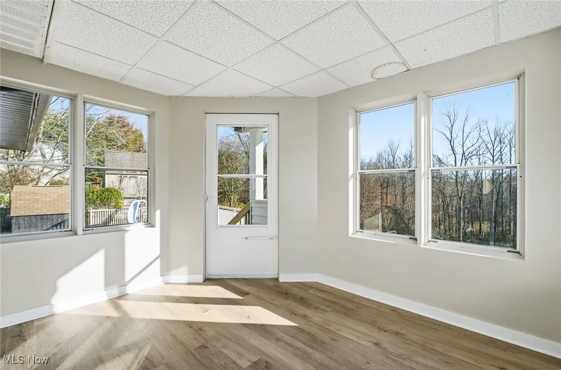Doorway to outside with wood finished floors and a paneled ceiling
