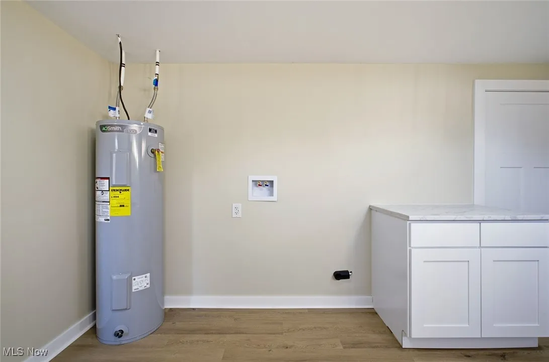 Laundry room with light wood finished floors, water heater, and washer hookup