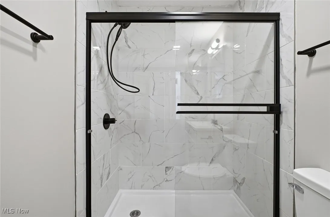 Full bath with a marble finish shower
