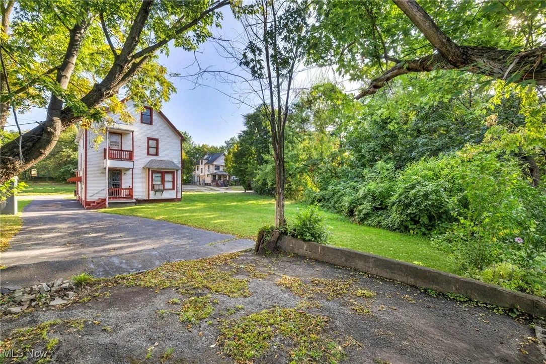 View of green lawn with a balcony and view of wooded area