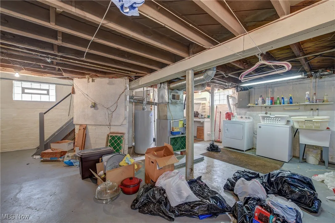 Basement with water heater, independent washer and dryer, heating unit, electric panel, and stairway