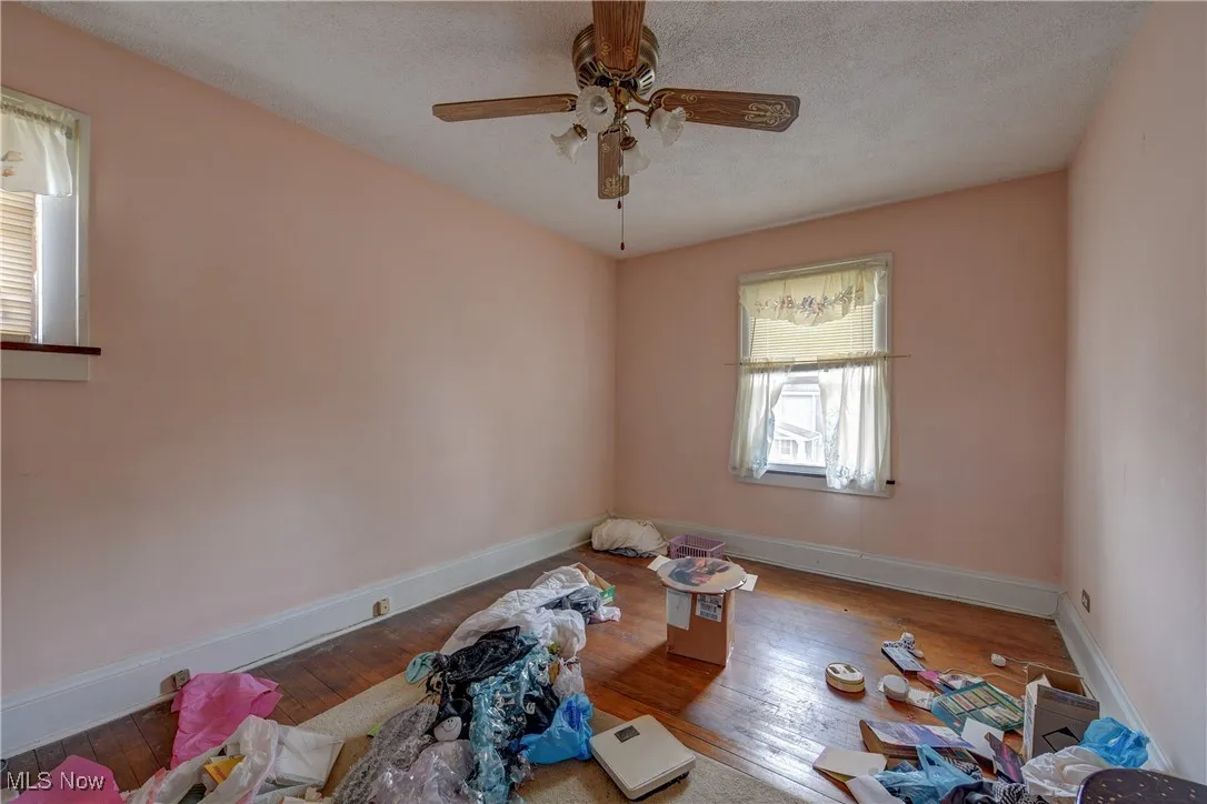 Empty room with wood-type flooring, a textured ceiling, and ceiling fan