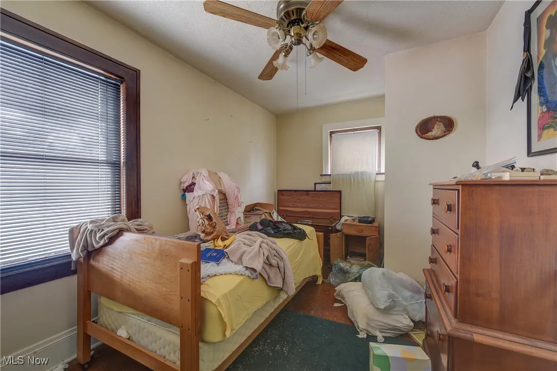 Bedroom featuring a ceiling fan, wood finished floors, and a textured ceiling