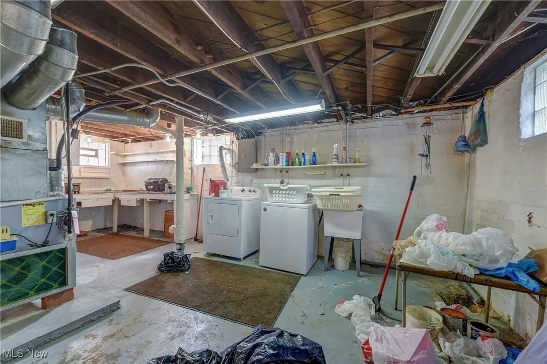 Basement featuring heating unit, washer and dryer, and electric panel