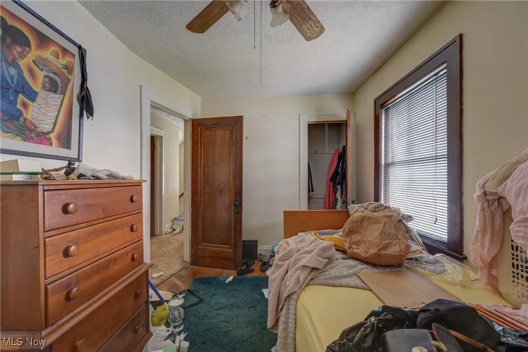 Bedroom featuring a textured ceiling, a ceiling fan, and a closet