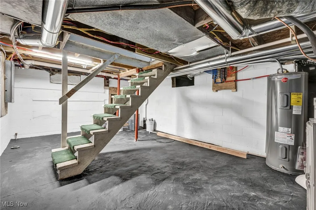 Unfinished below grade area featuring stairs, water heater, and electric panel